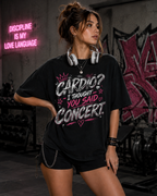 Woman wearing Concert Is My Cardio oversized black graphic tee in an edgy grunge gym setting