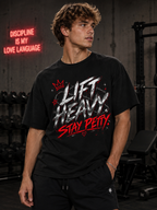 Man wearing Lift Heavy Stay Petty oversized black graphic tee in an edgy gym setting